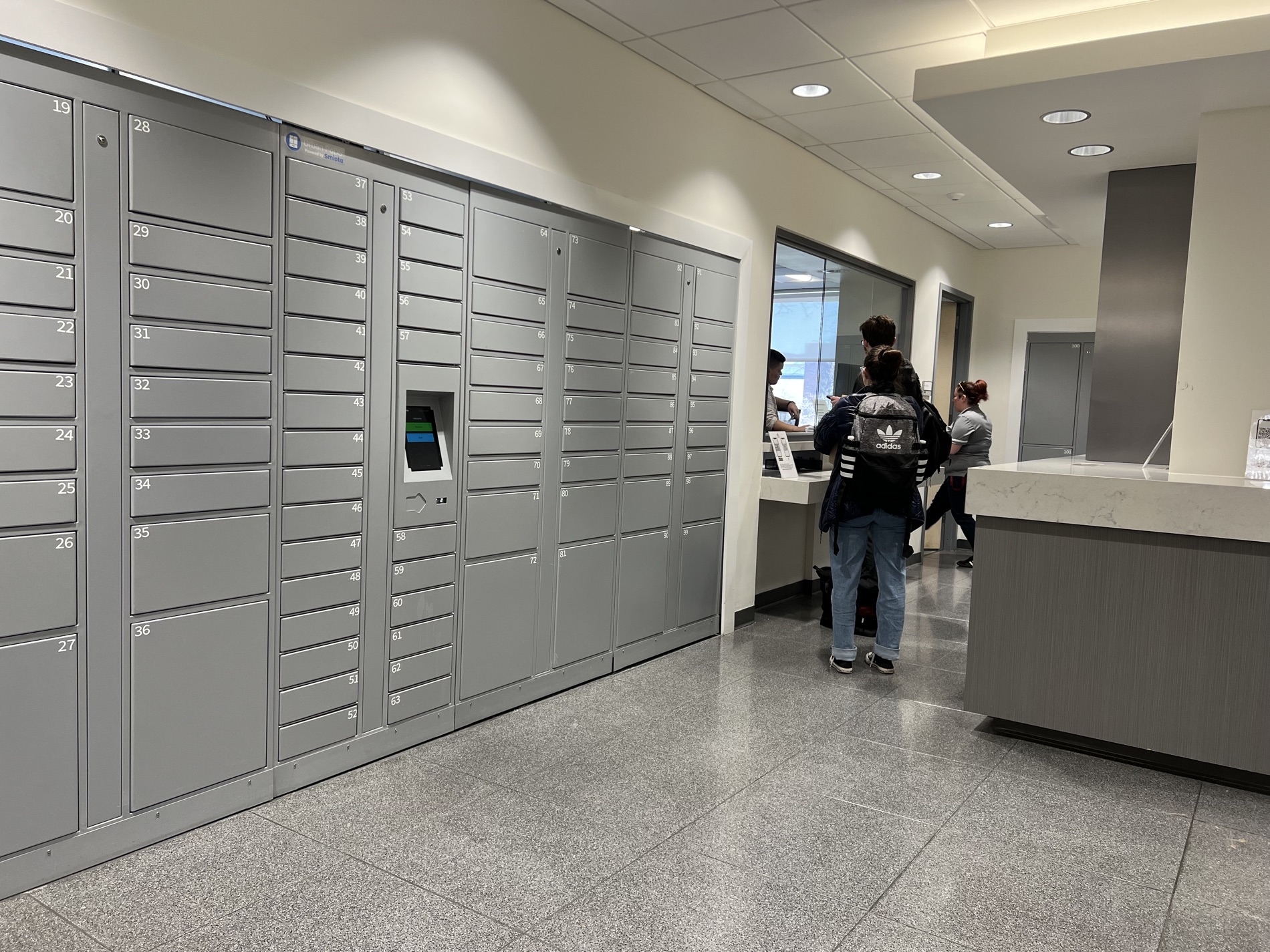 Students collecting mail and packages from Smiota smart lockers at a campus mailroom